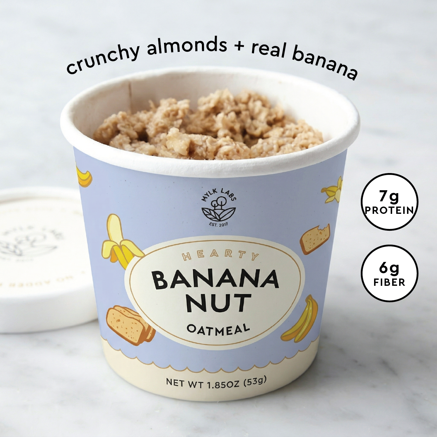 A container of Hearty Banana Nut Oatmeal from Mylk Labs, shown open with the banana nut oatmeal visible inside.