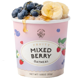 Mixed berry oatmeal in a pink container with fruit toppings on a white background