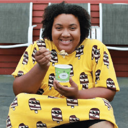 A person in a yellow dress eating oatmeal.